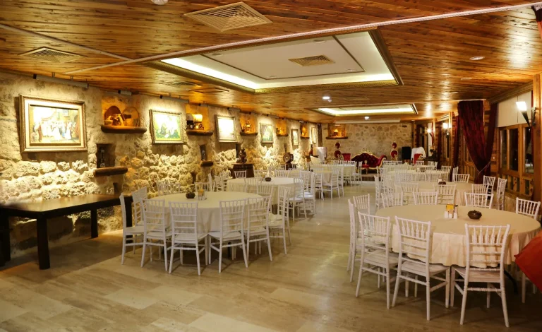 VIP Salonda yuvarlak davet masaları, taş duvarlar ve ahşap tavan